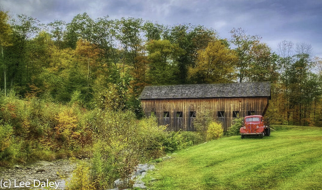 Privately owned Vermont covered bridge crosses creek uphill to owner's barn. Vintage 1940s Ford truck adds to the ambience.